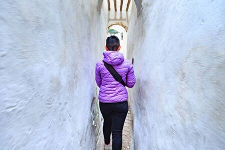 Unknown young woman walking in the old narrow street of Tetouan Medina quarter in Northern Morocco.の写真素材