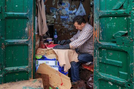 TETOUAN, MOROCCO - MAY 24, 2017: Unknown man works with leather goods in his street workshop in...