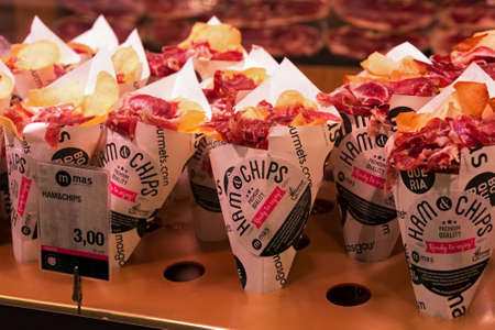 BARCELONA, SPAIN - MAY 16, 2017: Paper cornets with potatoes chips and sliced jamon as fast meat delicacies in the famous market La Boqueria in Barcelona.のeditorial素材