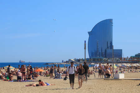 BARCELONA, SPAIN - MAY 15, 2017: Unknown people resting and sunbathing on a city beach. With view to the famous modern W Barcelona Hotel, popularly known as the Hotel Vela (Sail Hotel).のeditorial素材