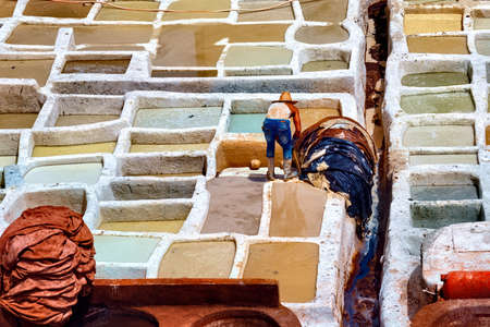Unknown woker in the tannery in Fez, Morocco. The tanning industry in the city is considered one of the main tourist attractions. The tanneries are packed with the round stone wells filled with dye.の写真素材