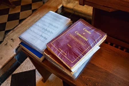 BERGAMO, ITALY - MAY 22, 2019: Books with christian songs on the wooden bench in the Catholic Church...