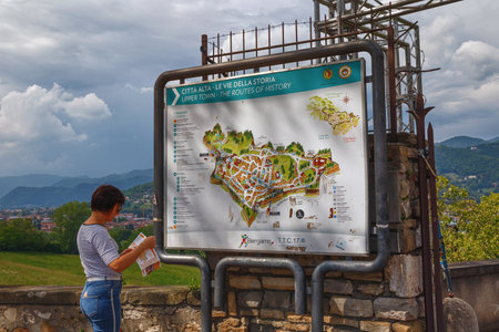 BERGAMO, ITALY - MAY 22, 2019: An unknown woman looking for landmarks of attractions on a tourist map of the Upper Bergamo (Citta Alta).のeditorial素材