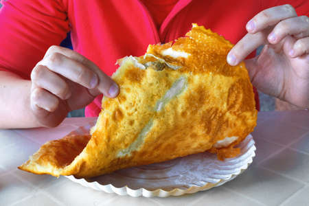 Fried cheburek in the hands of an unknown woman. Chebureki (deep-fried turnover with a filling of ground or meat and onions). It is made with a single round piece of dough folded in a crescent shape.の写真素材