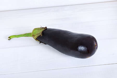 Purple eggplant on white wooden background.