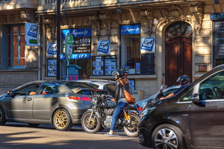 CANNES, FRANCE - JUNE 19, 2017: Unknown young woman in blue jeans sits on a motorcycle waiting for the traffic to start. Historic center of the Cannes.のeditorial素材