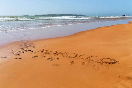 Morocco word is written on the sandy beach of the Atlantic ocean coast in Morocco.の写真素材