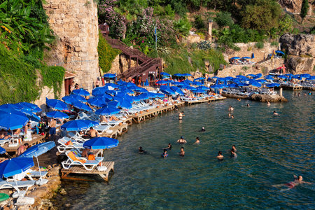 ANTALYA, TURKEY - JULY 08, 2018: Unknown people resting on the famous Mermerli beach (in historical part of city - Kaleici) in Antalya.のeditorial素材