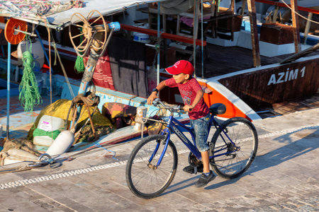 ANTALYA, TURKEY - JULY 08, 2018: Unknown young boy riding a bicycle near the Mediterranean sea coast in Antalya harbor.のeditorial素材