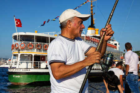 ISTANBUL, TURKEY - JULY 06, 2018: Unknown man with a rod is fishing in the Bosphorus near the Galata Bridge.のeditorial素材