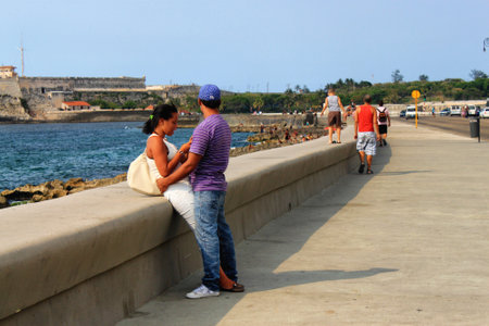 HAVANA, CUBA - MAY 15, 2012: An unknown young couple on the Malecon promenade (officially Avenida de Maceo), with Morro Castle (also known as Castillo de los Tres Reyes del Morro) on the background.のeditorial素材