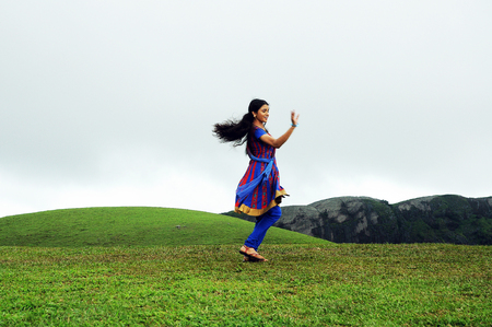 KODAIKANAL, INDIA - JUNE 30TH, 2015: Young woman dancing on the hillのeditorial素材