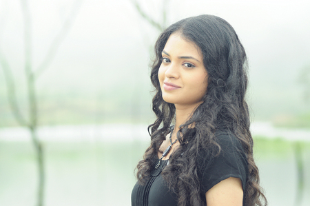 OOTY, INDIA - 30 JUNE, 2015: Cute young woman with beautiful smile posing near the pond.のeditorial素材