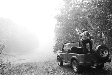 Black & White close up blue old Jeep car parking on the India.man jumping outside at car