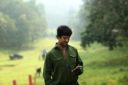 Young happy smiling man with mobile phone in a park.のeditorial素材