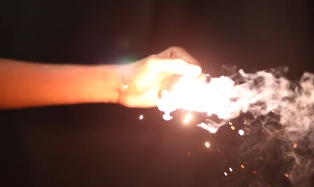 hand holding sparklers over black backgroundsの写真素材