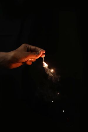 Hand holding burning Sparkler blast on a black backgroundsの写真素材