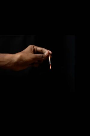Hand holding an extinguished matchstick on black backgroundsの写真素材