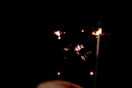 Close-up child hand holding fire sparklers on dark at festival