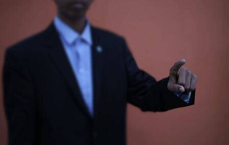 Businessman in black suit is pointing his finger to touch