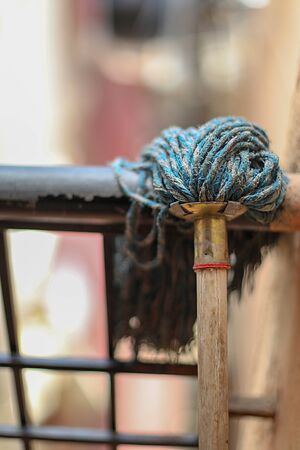 mop floor broom drying on the fence outdoorsの写真素材