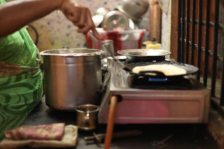 The woman standing next to stove and preparing dinner in the kitchen.の写真素材