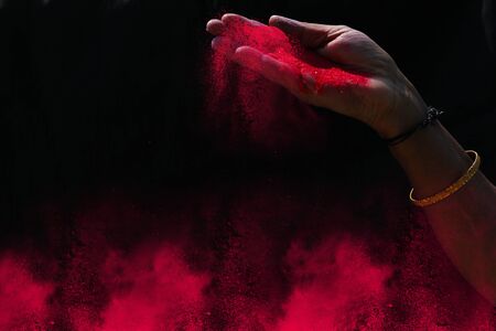 Closeup hand red colour holi powder splash at black backgroundsの写真素材