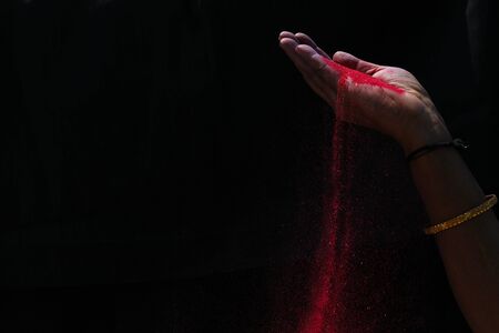 Closeup hand red colour holi powder splash at black backgroundsの写真素材