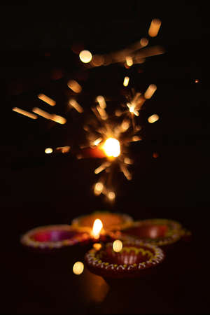Diya lamps on a reflective base with firecrackers glittering bokeh background