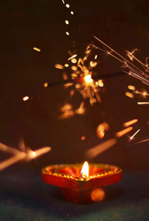 Diya lamps on a reflective base with firecrackers glittering bokeh background