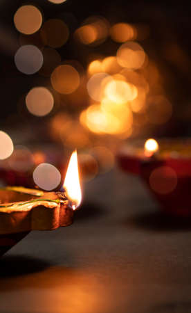 Diya lamps on a reflective base with glittering bokeh background