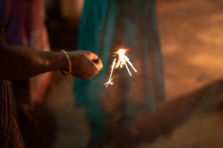 A selected focus shot of an Indian woman holding a firecracker