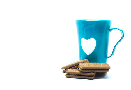 Selective focus photo of a cup of tea with chocolate cream biscuitの写真素材