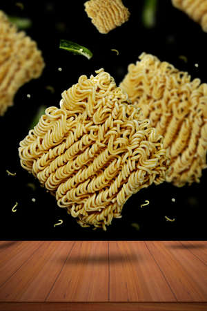 Instant noodles with green chillies flying against a dark backgrounds
