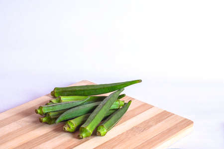 ladies finger or okra on the cutting board against a white backgrounds.の写真素材