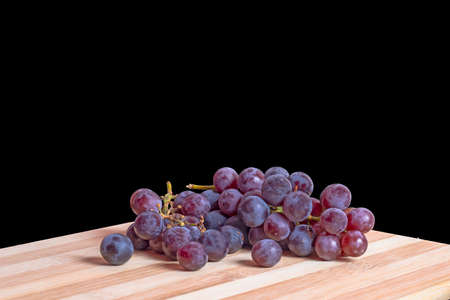 Fresh red grapes on a wooden table against a dark background.の写真素材