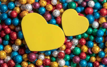 Valentine's Day backgrounds. Multicolor small size thermocol decorative balls with two yellow hearts on topの写真素材