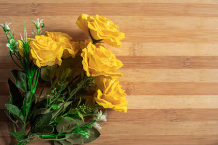 Valentine's Day background with a bouquet of yellow roses on a wooden tableの写真素材