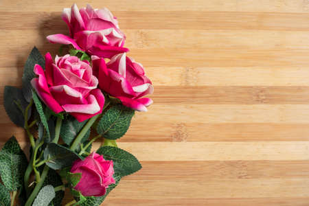 Bouquet of pink plastic roses on a wooden table, copy spaceの写真素材