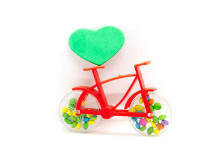 Valentine's Day. Red Plastic bicycle toy with green heart on white backgrounds.の写真素材