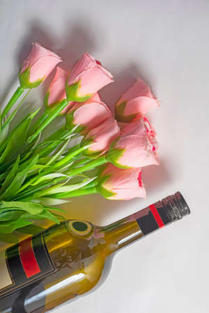 Valentine's Day background. Wine bottle with bouquet of pink roses on isolated white background.の写真素材