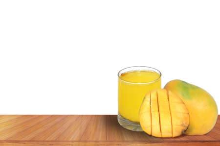 Fresh tropical mango juice with beautiful ripe sliced mangoes on a wooden table isolated on white backgroundの写真素材
