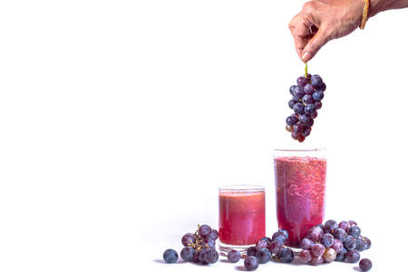 A bunch of red grapes and fresh grape juice on a white background. woman holds a bunch of grapes.の写真素材