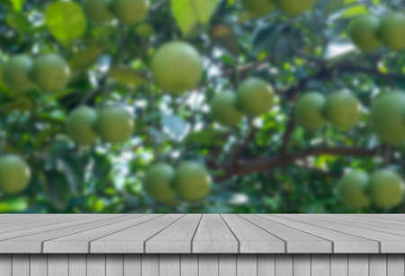 Wooden table with oranges or sweet lime hanging on tree background. For display your products.