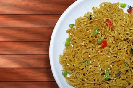 Fried instant noodle with vegetables on white plate on wooden backgroundの写真素材