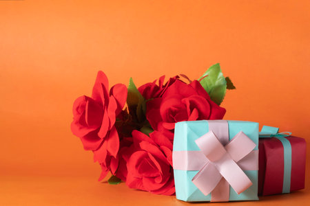 Bouquet of red roses and gift box on orange background. Valentines day concept.の写真素材