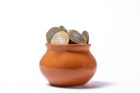 Coins in a clay pot on a white background. Saving concept.の写真素材