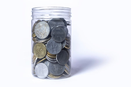 Coins in glass jar isolated on white background with copy space. Saving concept.