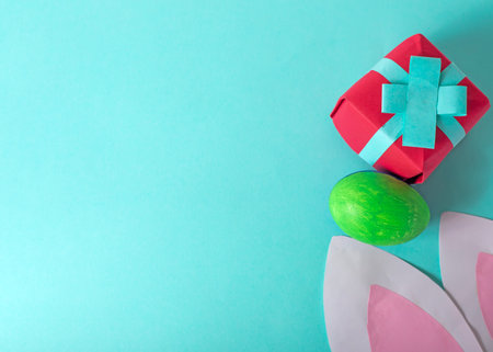Easter eggs with rabbit ears and gift box on turquoise background. Top view