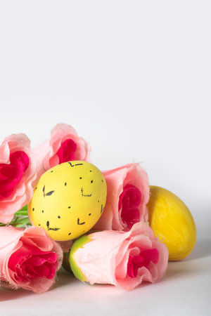 Easter eggs and pink rose flowers on a white background with space for text. Easter concept.の写真素材